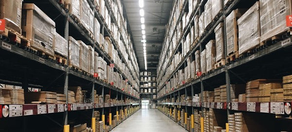 Warehouse aisle with tall pallet racking lit by linear high-bay fixtures