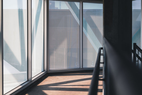 Empty corner room with floor-to-ceiling windows and daylight falling across the floor